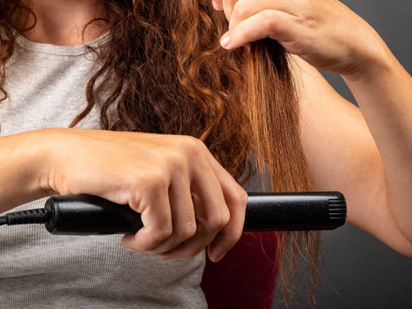 Mladá žena si prohlíží padající vlasy v ruce – ilustrační foto k článku o návycích, které způsobují padání vlasů